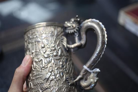 A mid-19th century Chinese silver mug, the body featuring warriors fighting to one side, with inscribed shield plaque H.13cm.